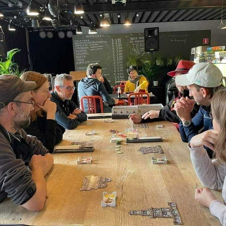 hommes et femmes autour d'une table en train de jouer à un jeu de société